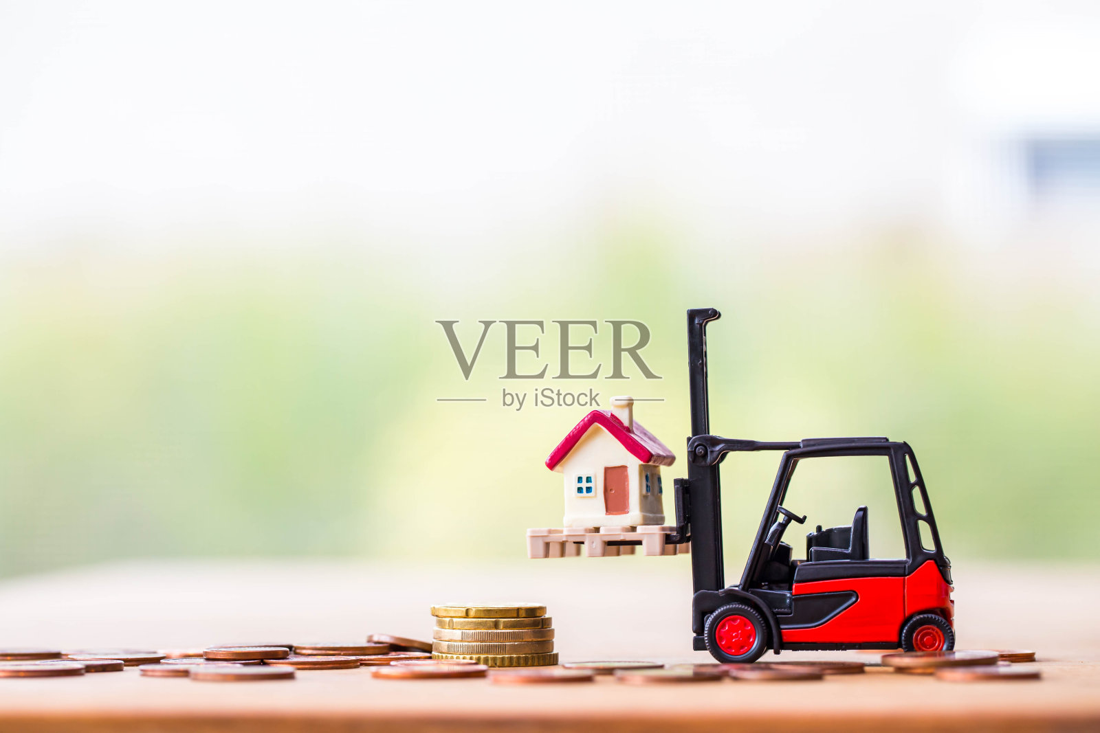 小小的家用微型玩具铲车堆叠硬币，以模糊的春天花园为背景。照片摄影图片