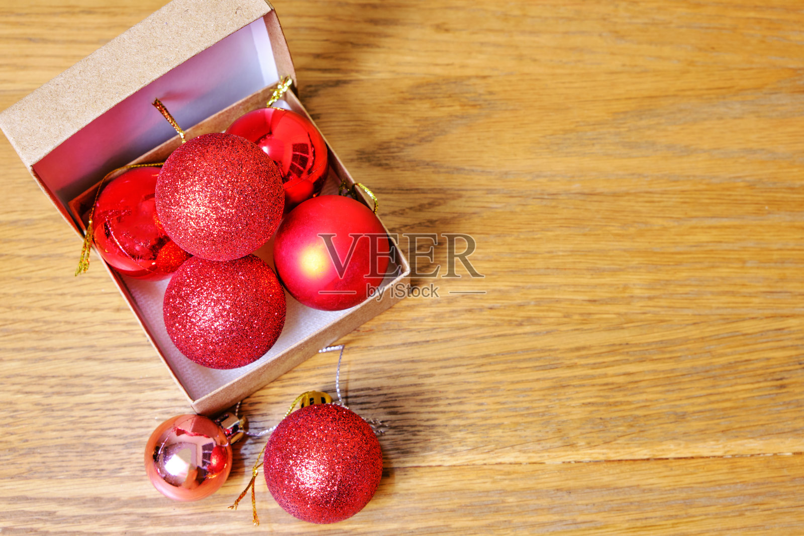 被光击中的红球和木制桌子上的绿叶。情人节和圣诞节的概念照片摄影图片