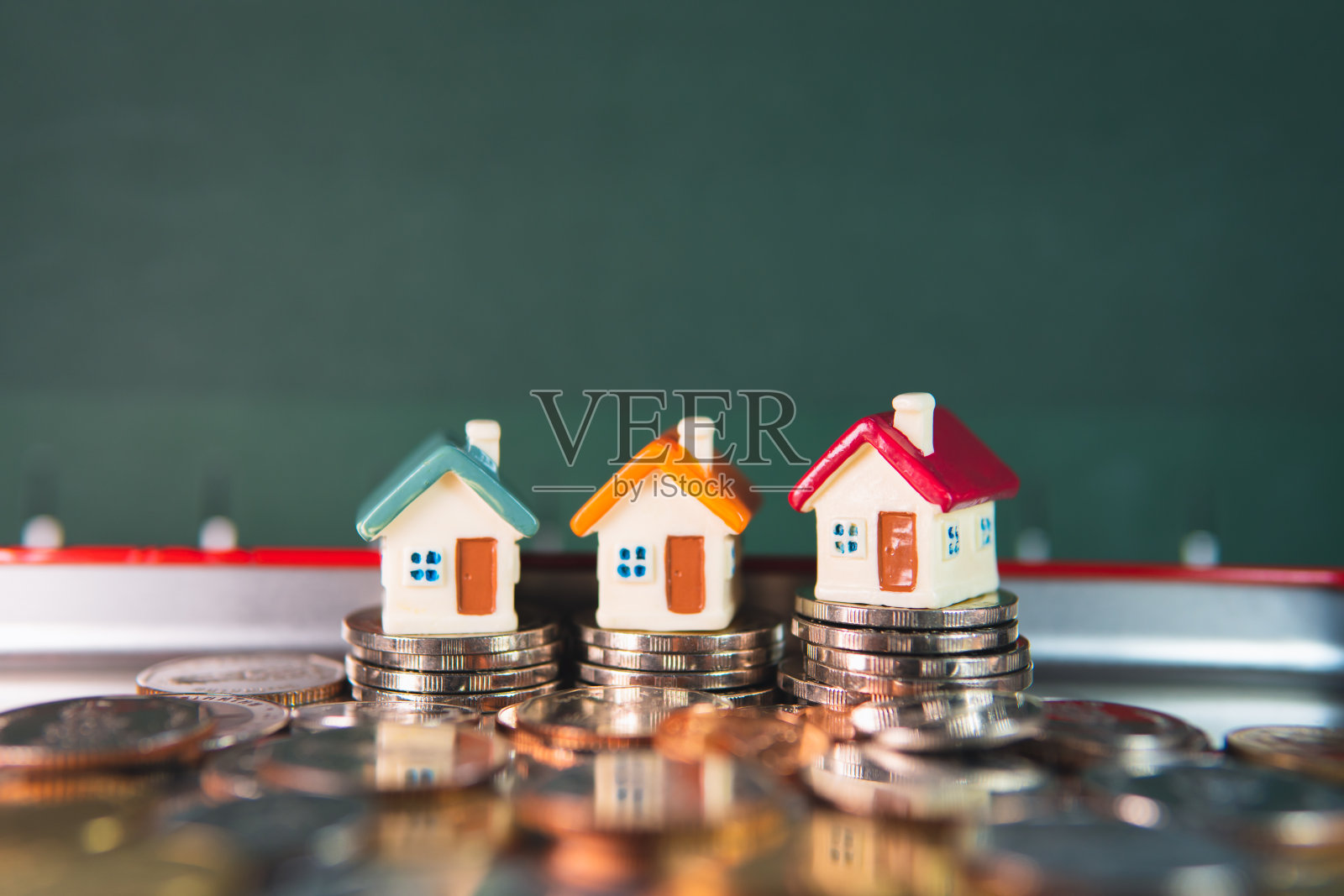 微型彩色房子上堆叠硬币照片摄影图片