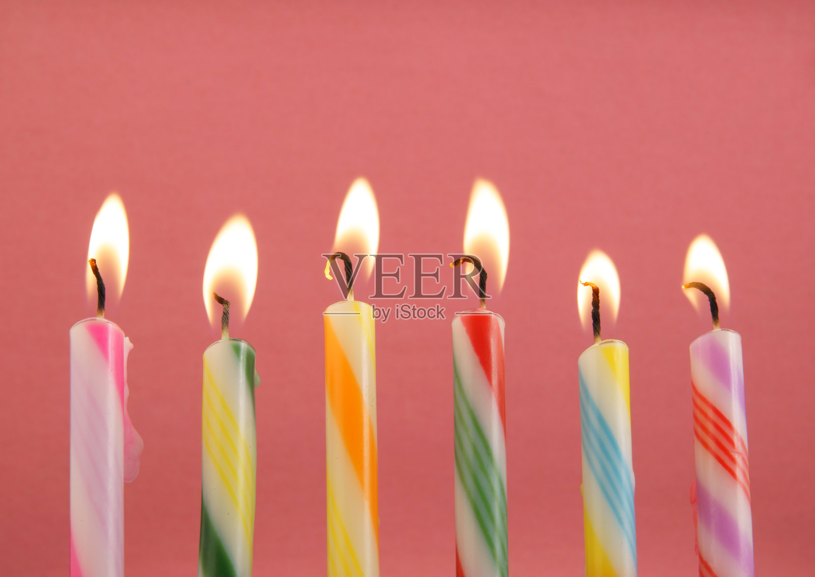 粉红色背景上的彩色生日蜡烛照片摄影图片