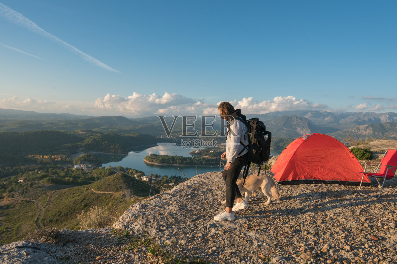 一个年轻人和她的狗在山顶露营照片摄影图片