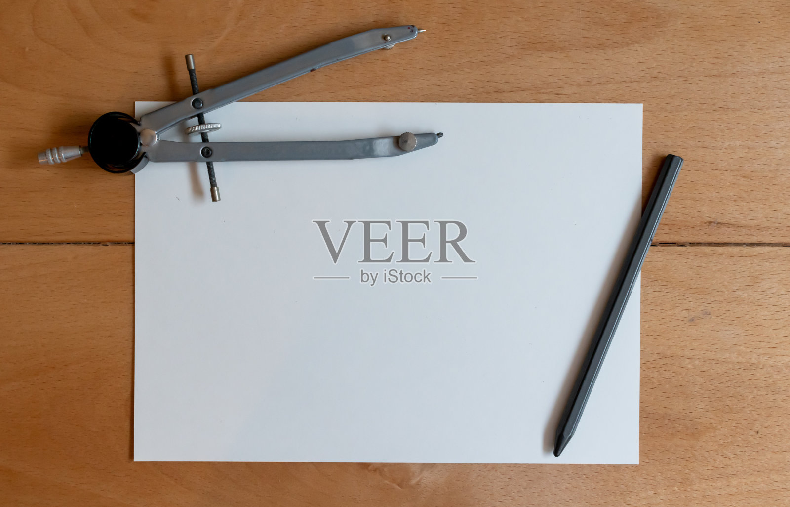 一张白纸，一个老式的金属指南针和一支现代的铅笔，放在一张老式的木制书桌上照片摄影图片