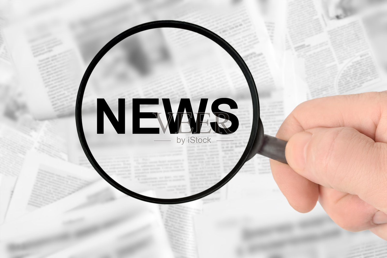 男人手中的放大镜，在报纸抽象模糊背景上的新闻铭文。媒体概念照片摄影图片