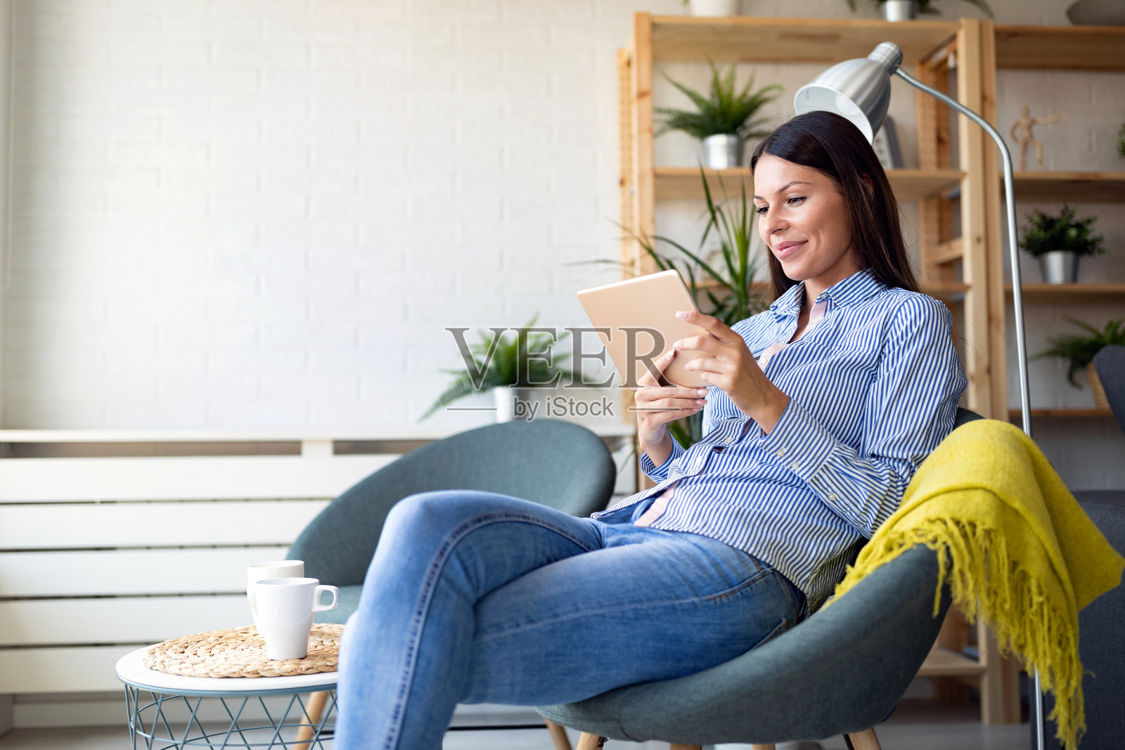 美丽的年轻女子放松在家里与数字平板电脑照片摄影图片