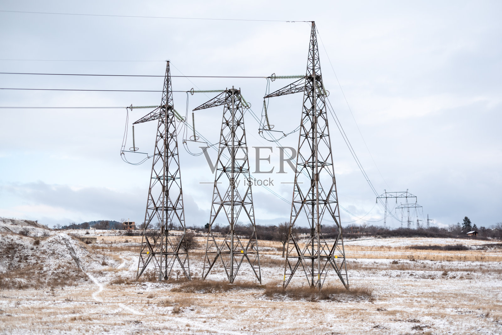 高压电气支持。阴天三柱对称距离长在冬天寒冷雪白。能源行业。电流通过电线。文本的空闲空间。照片摄影图片