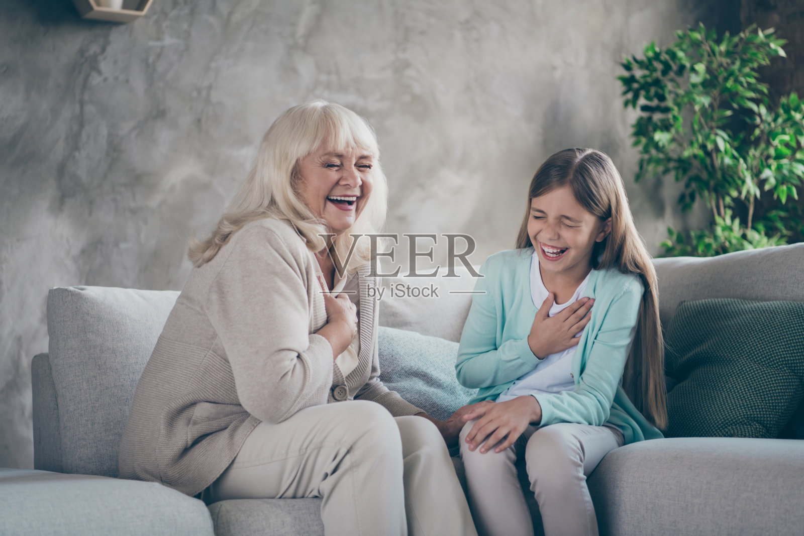 照片的愉快积极幽默友好的亲戚一起笑着讲故事奶奶开玩笑她的青春时代坐在沙发上照片摄影图片