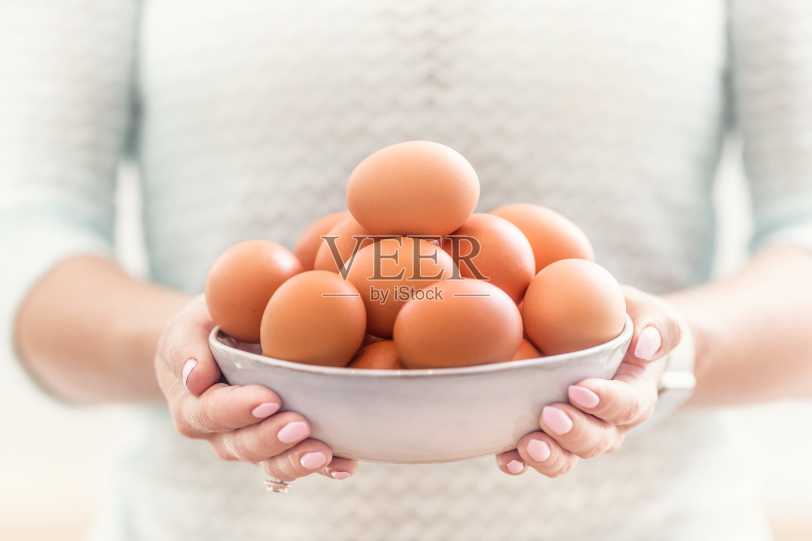 一个年轻女子的手拿着一碗鸡蛋。照片摄影图片