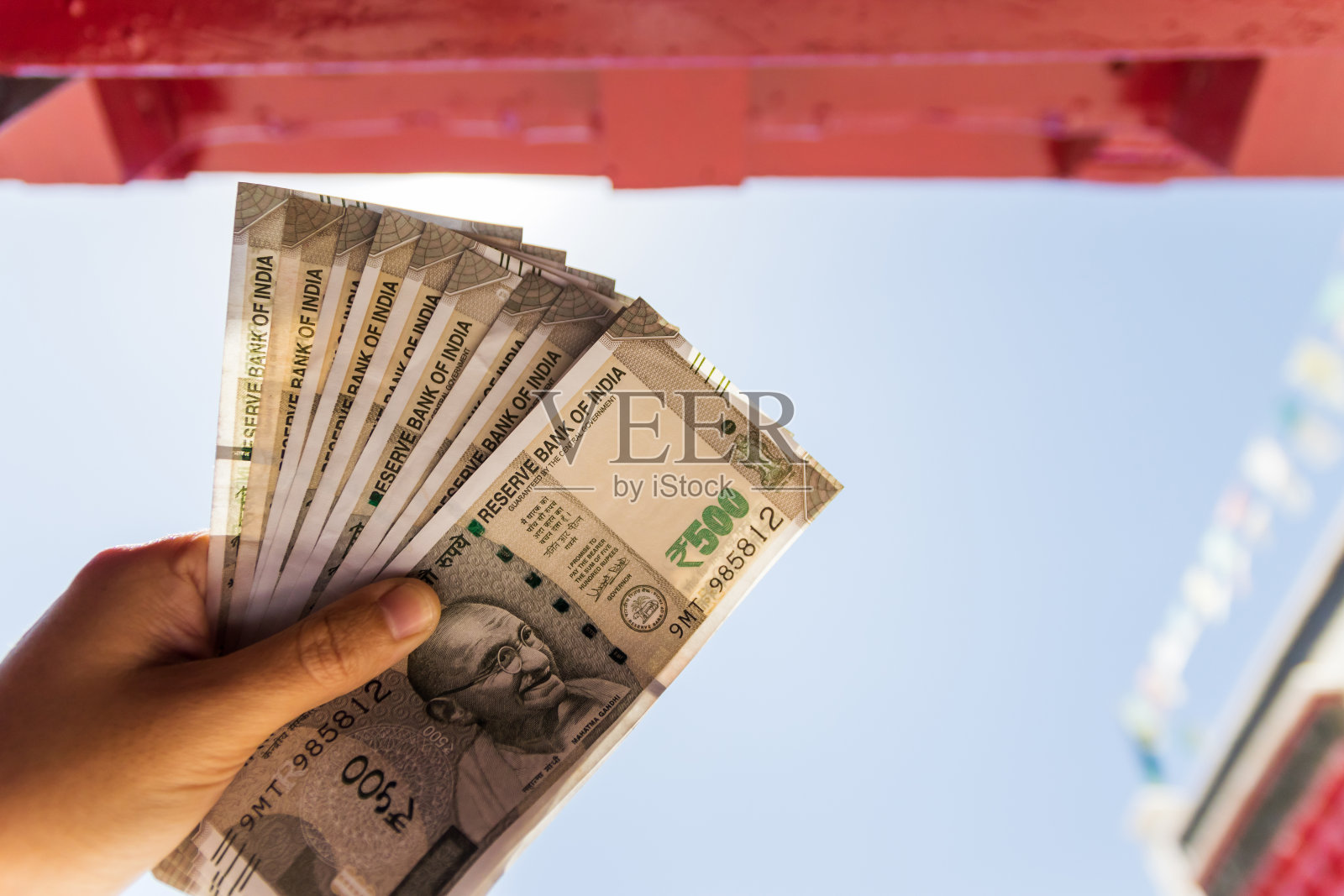 手持印度新版五百卢比纸币，背景是印度北部建筑。准备旅行和花钱体验新生活。照片摄影图片