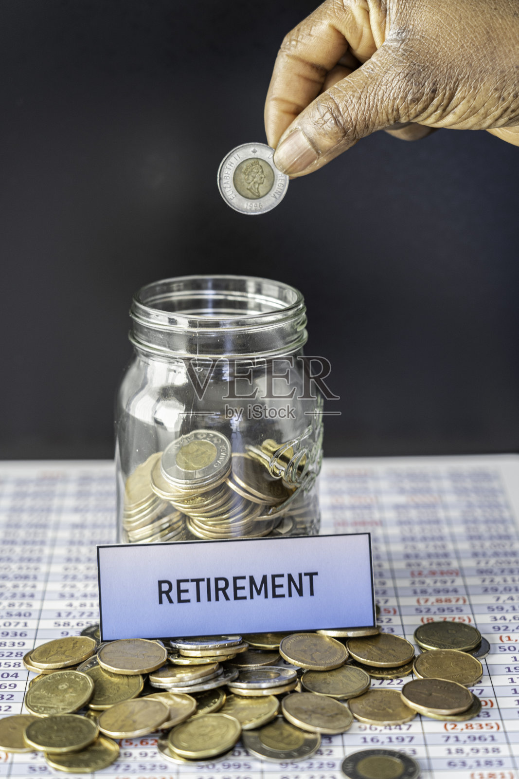 显示退休储蓄电子表格上的硬币罐照片摄影图片