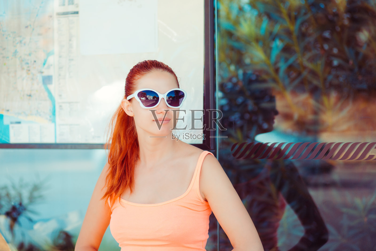 那位年轻的红头发妇女站在公共汽车站等公共汽车照片摄影图片