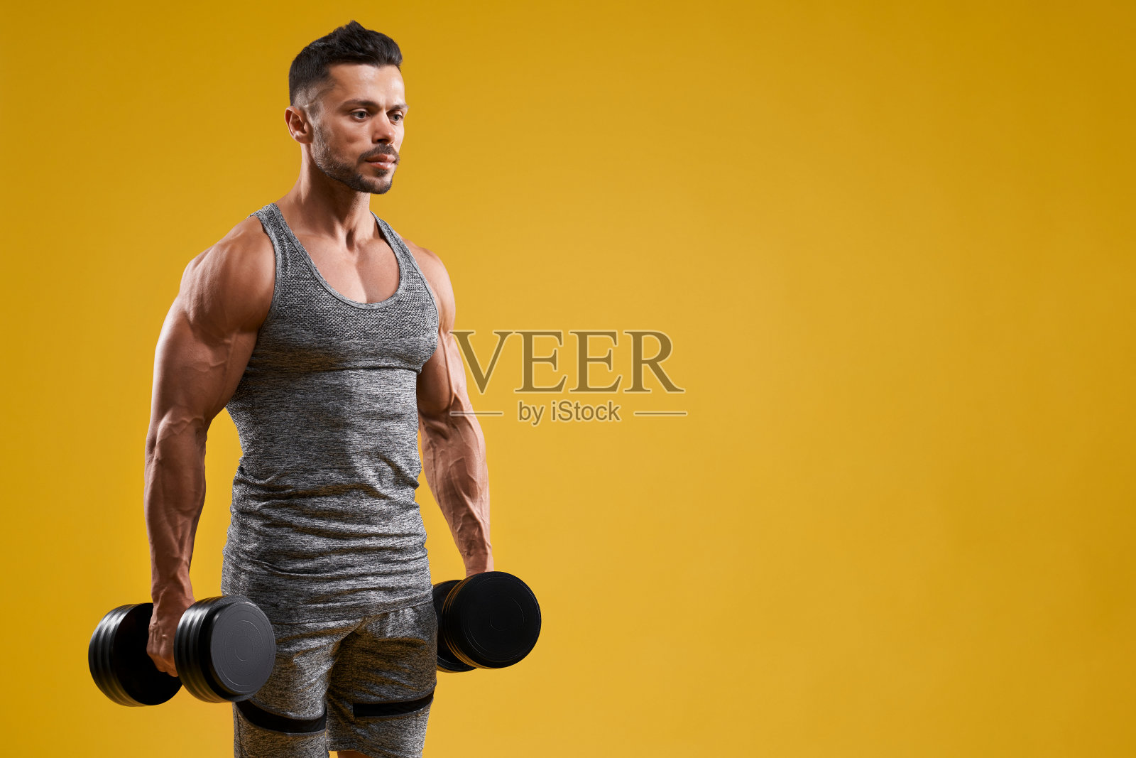 举着哑铃的健壮年轻人照片摄影图片