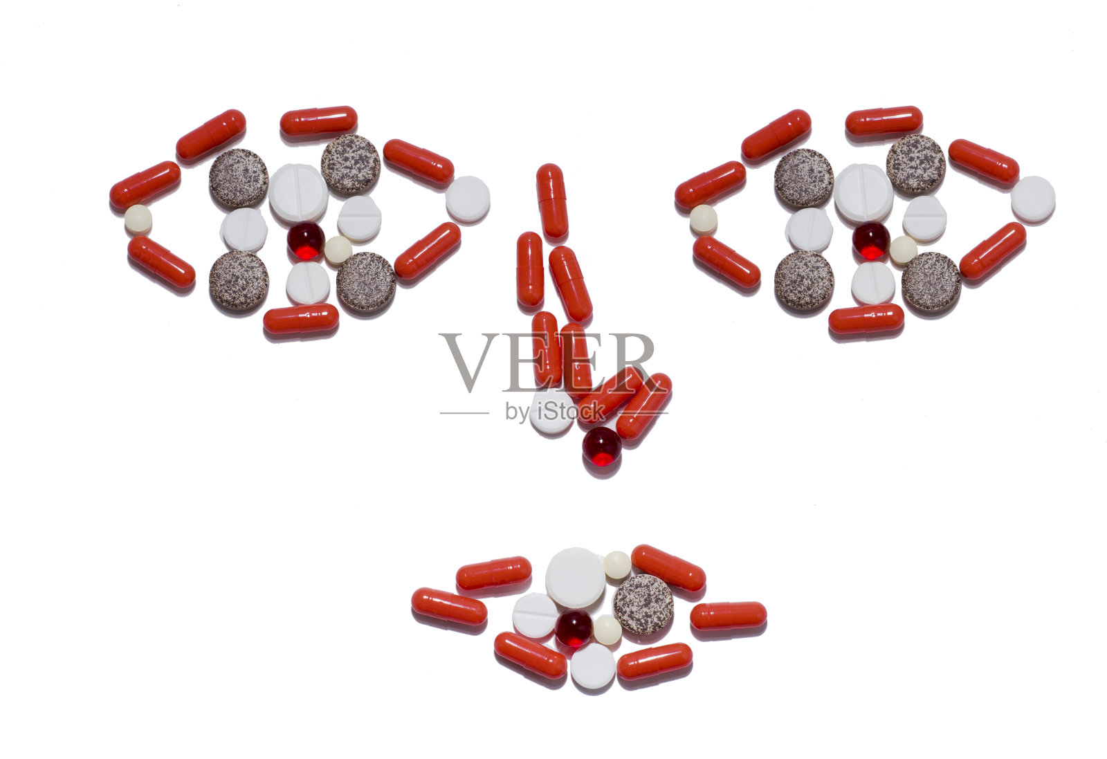 一大把不同颜色和形状的药片，在白色背景上形成人脸的形状。隔离。病毒防护照片摄影图片