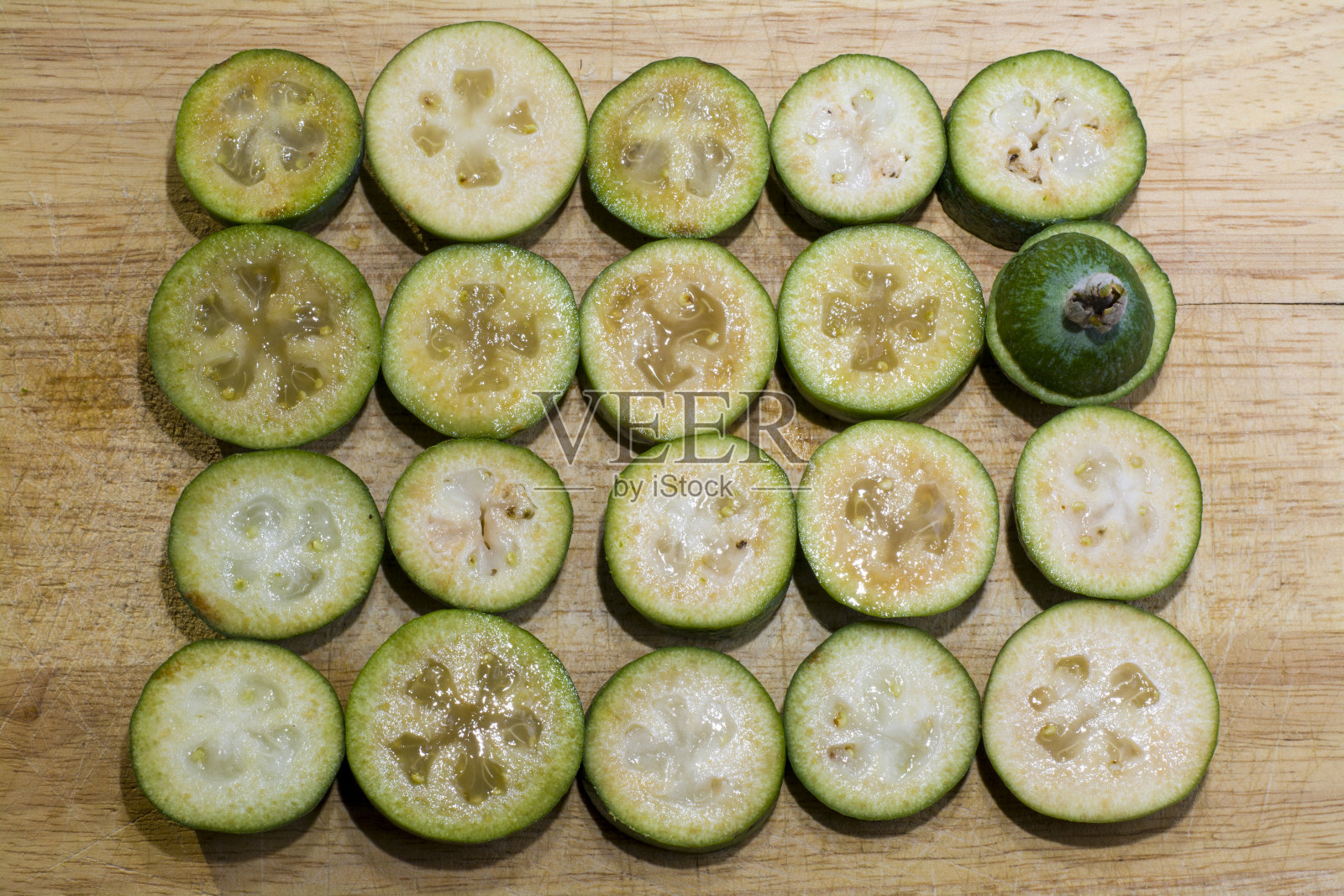 多汁的绿色飞花果，切成圆圈。在木制的背景上照片摄影图片