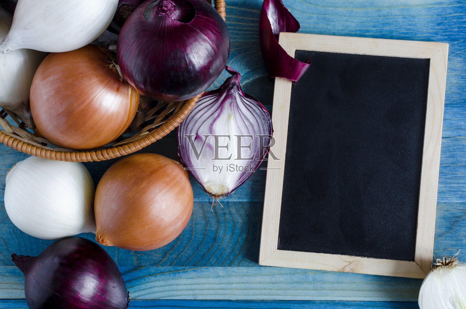 红色，白色和米色的洋葱在蓝色背景的深色标识上作为文本照片摄影图片