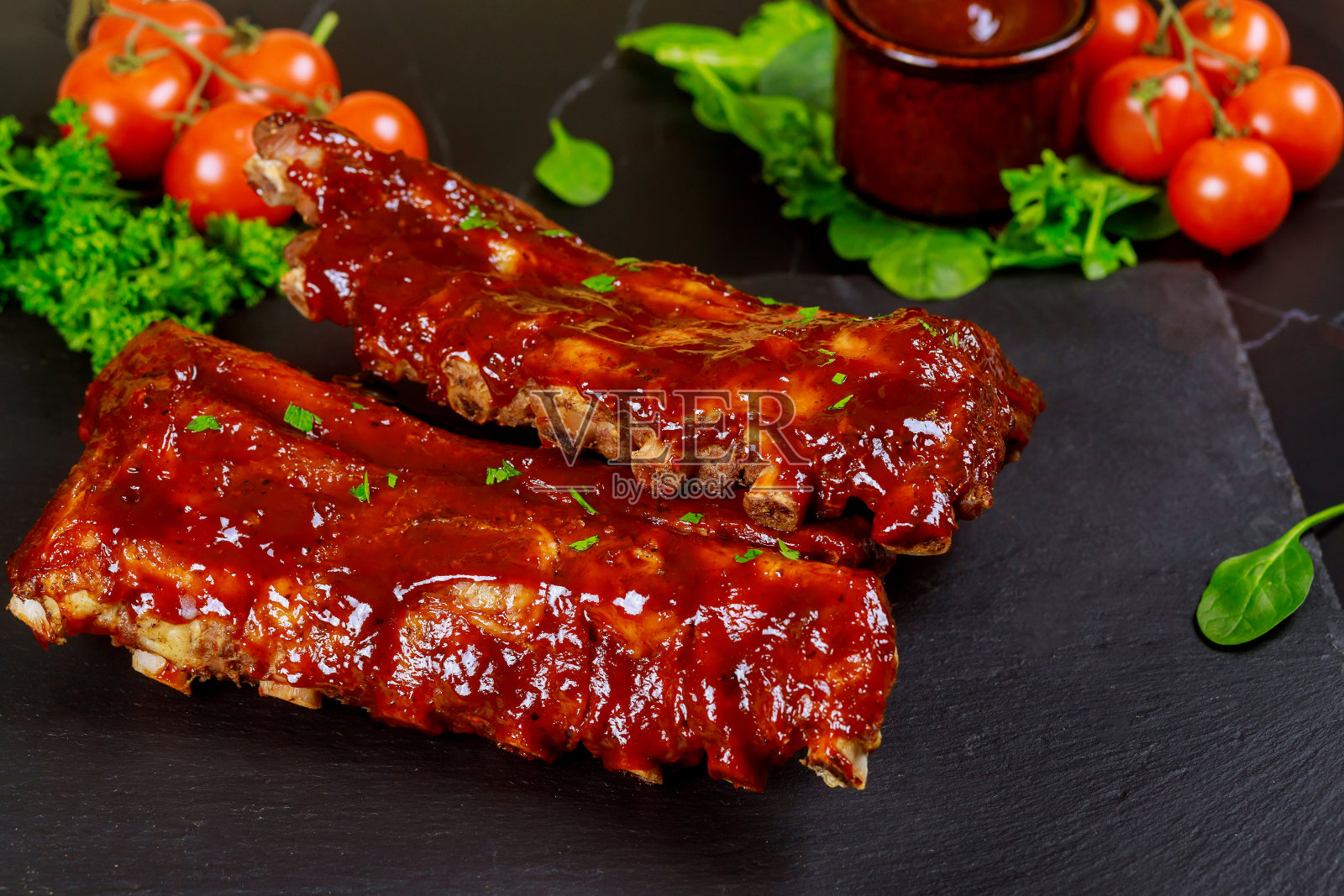 多汁烤排骨配番茄、沙司和欧芹。照片摄影图片