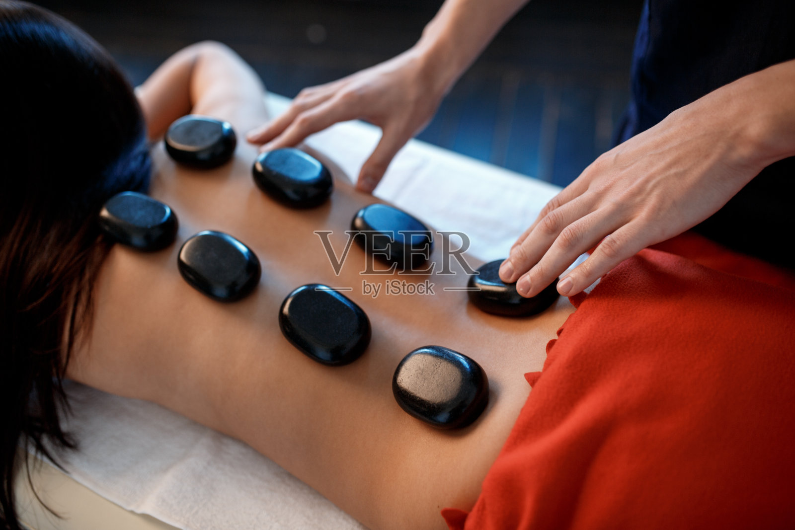 年轻的亚洲女人在豪华水疗和健康中心享受传统热石按摩的治疗效果照片摄影图片