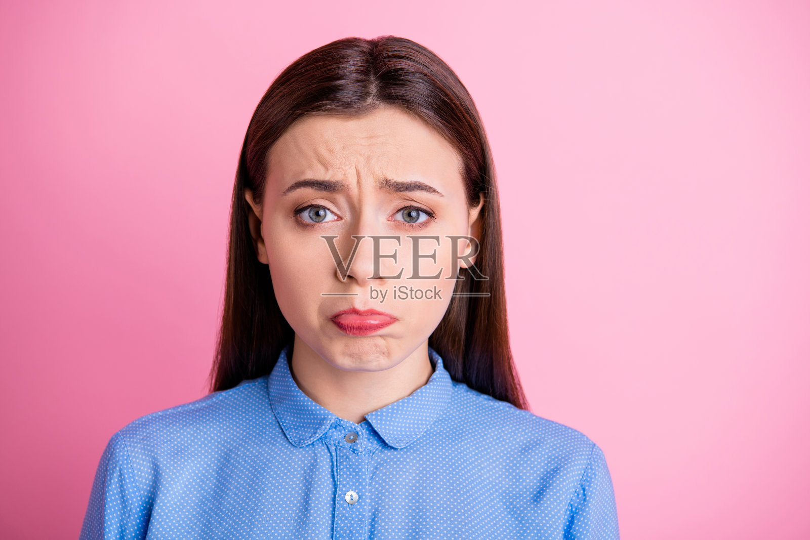 照片漂亮的女士与冒犯看和可爱的面部表情操纵男友请求原谅穿蓝色点衬衫孤立的粉红色背景照片摄影图片