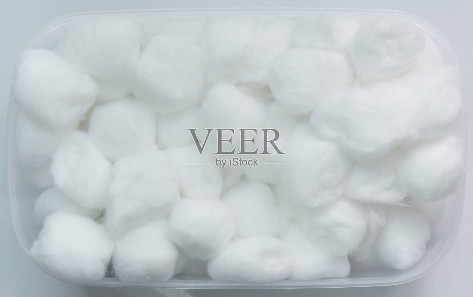 无菌棉球置于白色塑料盒内，白色背景。照片摄影图片