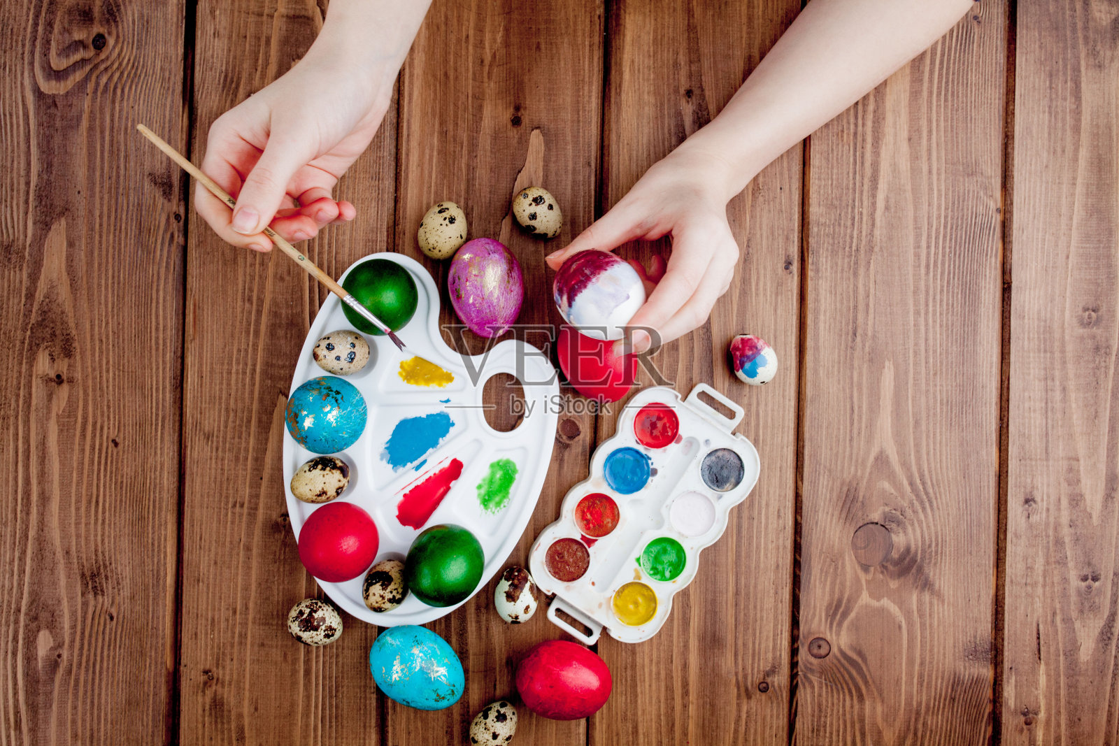 手绘复活节彩蛋、颜料和画笔，在木制背景上绘制图案照片摄影图片
