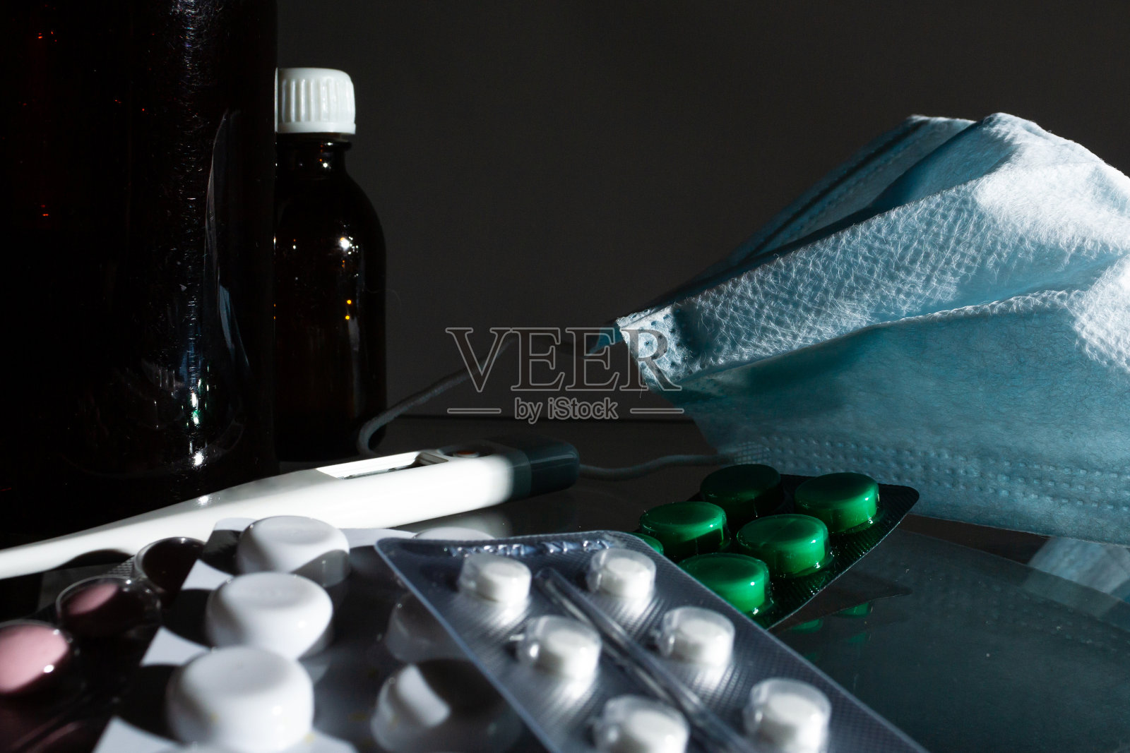 药瓶、温度计、注射器、纱布和药片，药片在玻璃灰色的背景上近观。本空间照片摄影图片