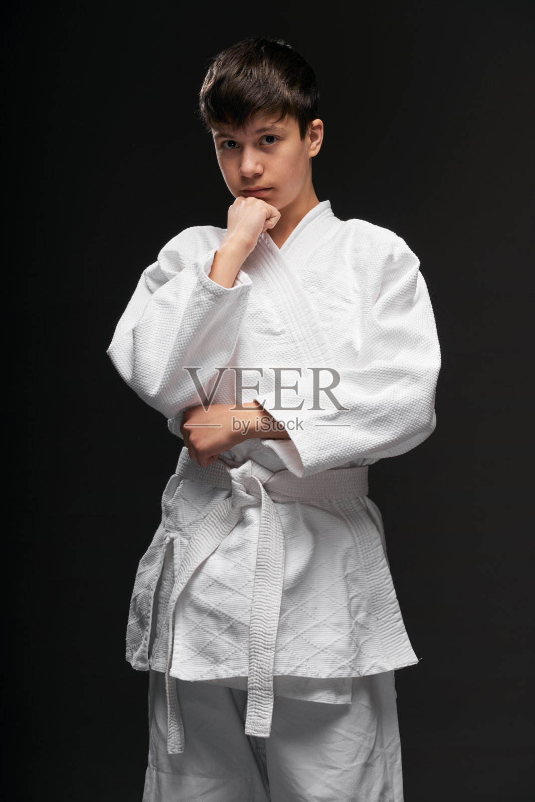 穿着武术服的青少年在深灰色背景上摆姿势，运动概念照片摄影图片