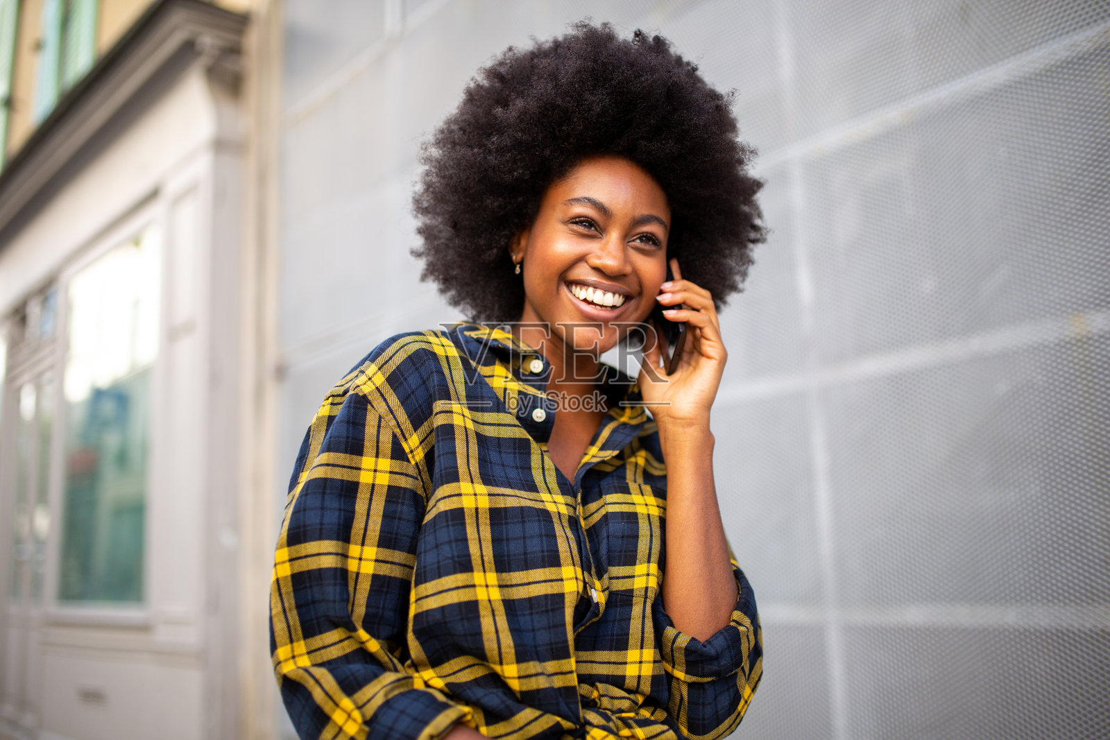 年轻的黑人妇女走在街上边走边用手机打电话照片摄影图片
