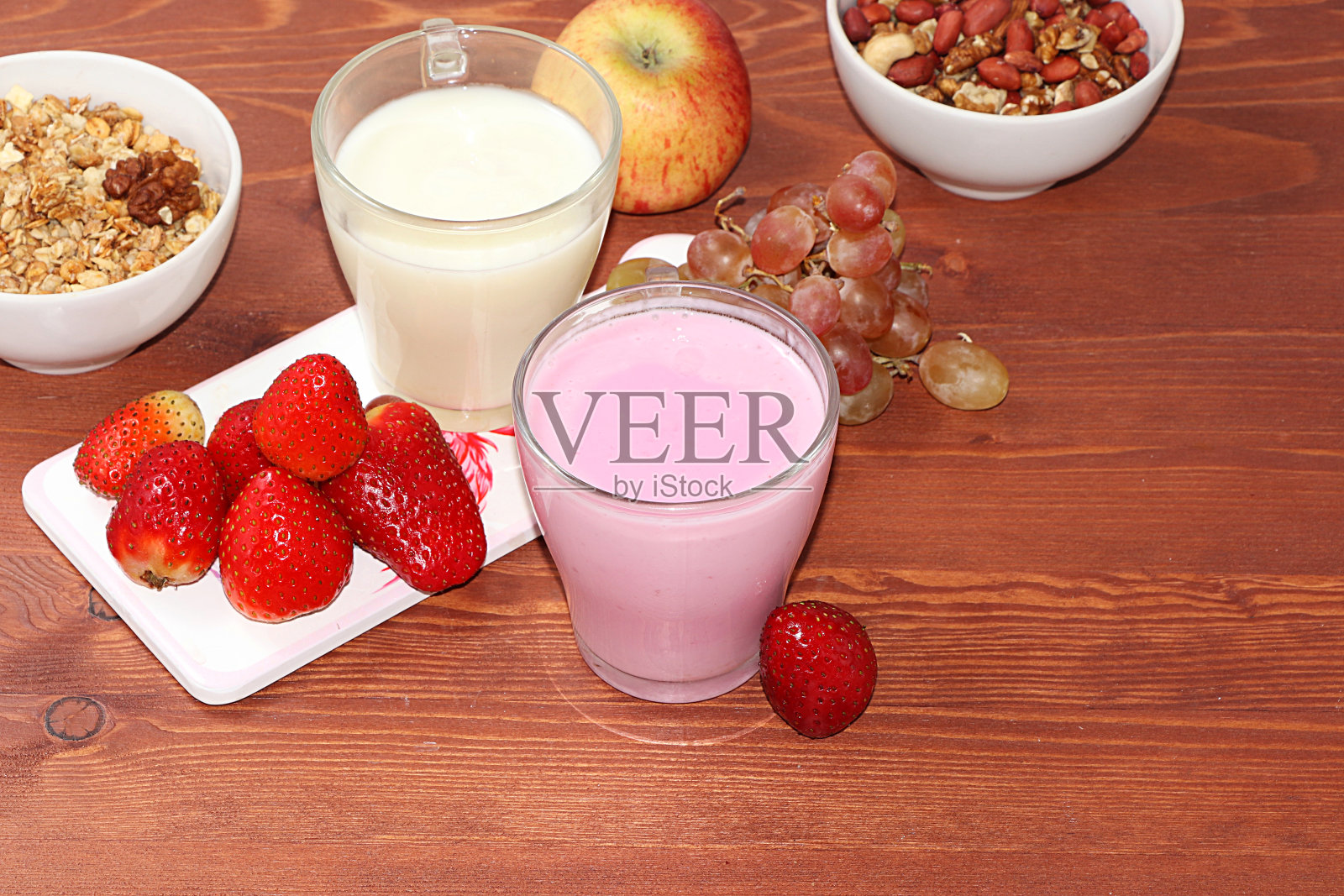 草莓苹果奶昔和格兰诺拉麦片，格兰诺拉麦片，新鲜的浆果，苹果，草莓和葡萄在一个木制的阳光背景。健康天然食品的概念。健康早餐，儿童食品，选择性重点，俯视图照片摄影图片