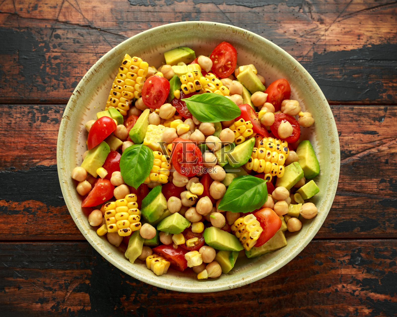牛油果鹰嘴豆沙拉配烤甜玉米，番茄和罗勒。健康的素食照片摄影图片