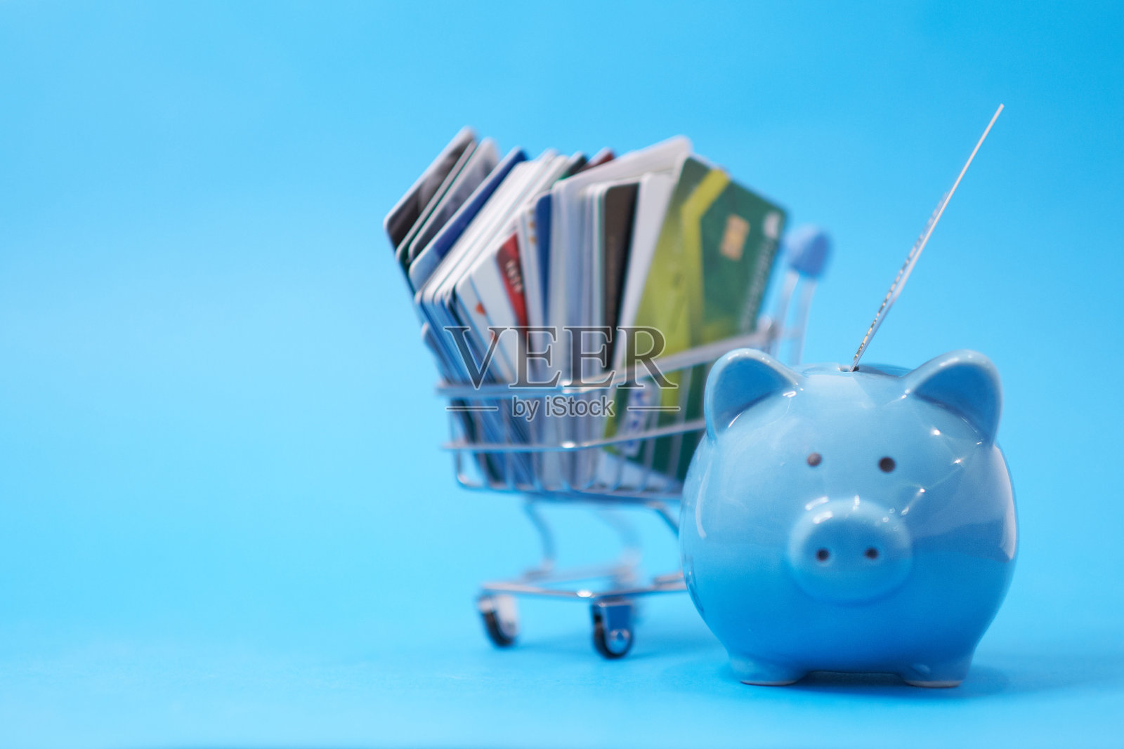 存钱罐和一堆信用卡，财务浪费。债务重组，财务困境，重新协商其拖欠债务。一堆堆色彩鲜艳的打折塑料卡，近距离观看，照片摄影图片