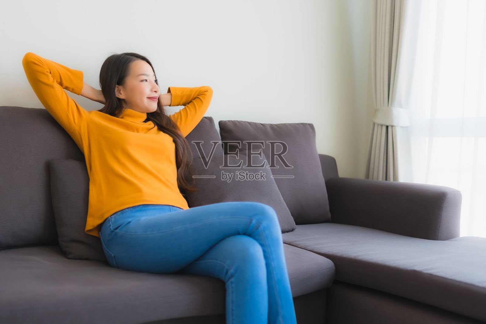 在客厅沙发椅上放松微笑的年轻亚洲女性肖像照片摄影图片