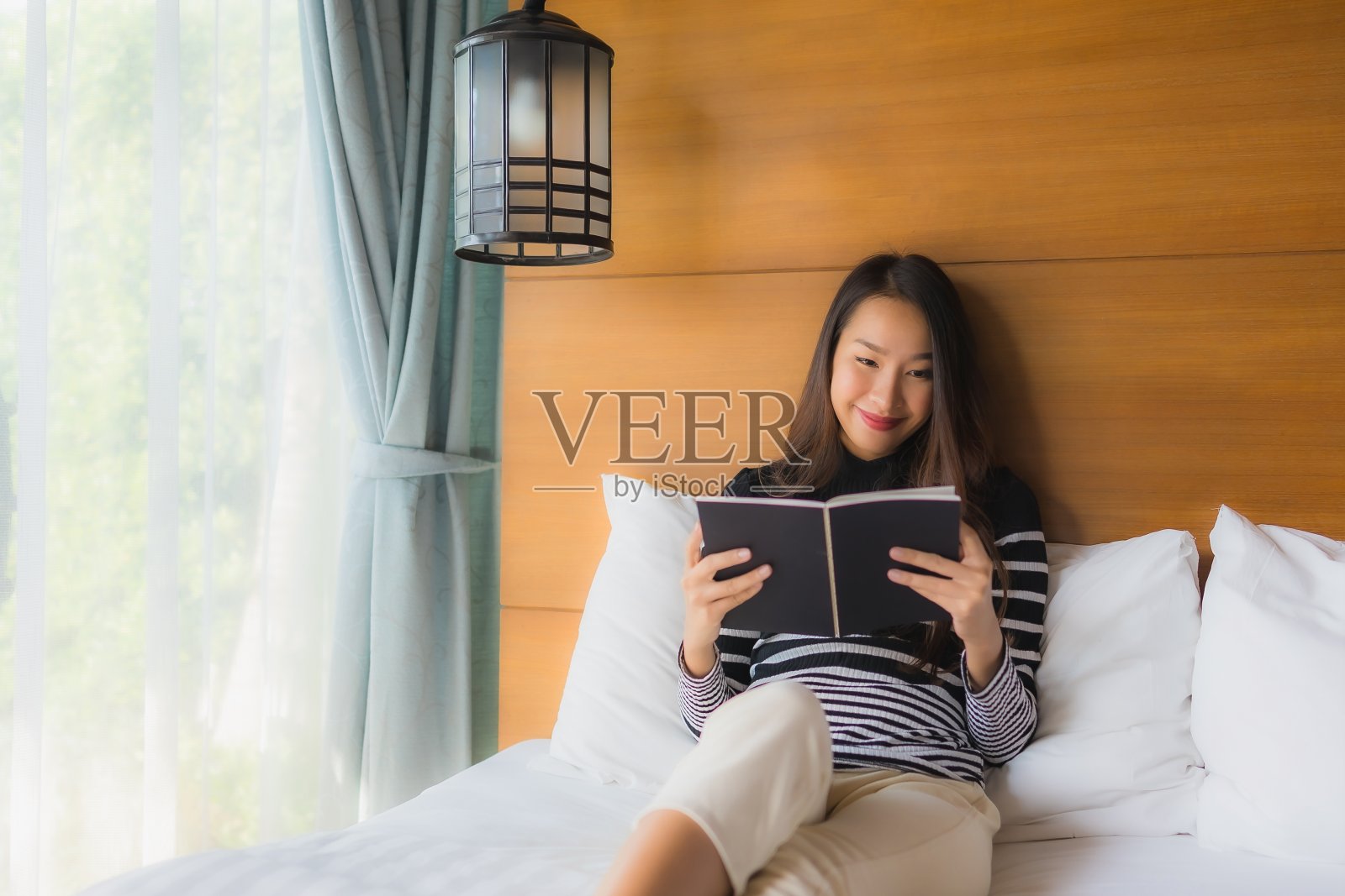 在卧室里看书的年轻亚洲女性肖像照片摄影图片