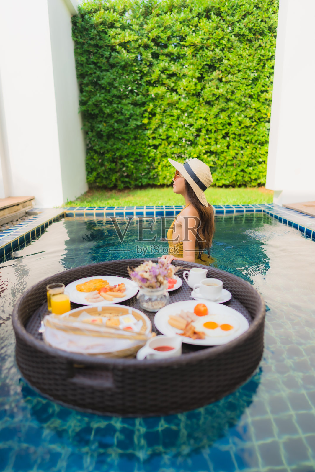 年轻亚洲女子在泳池享用漂浮早餐照片摄影图片