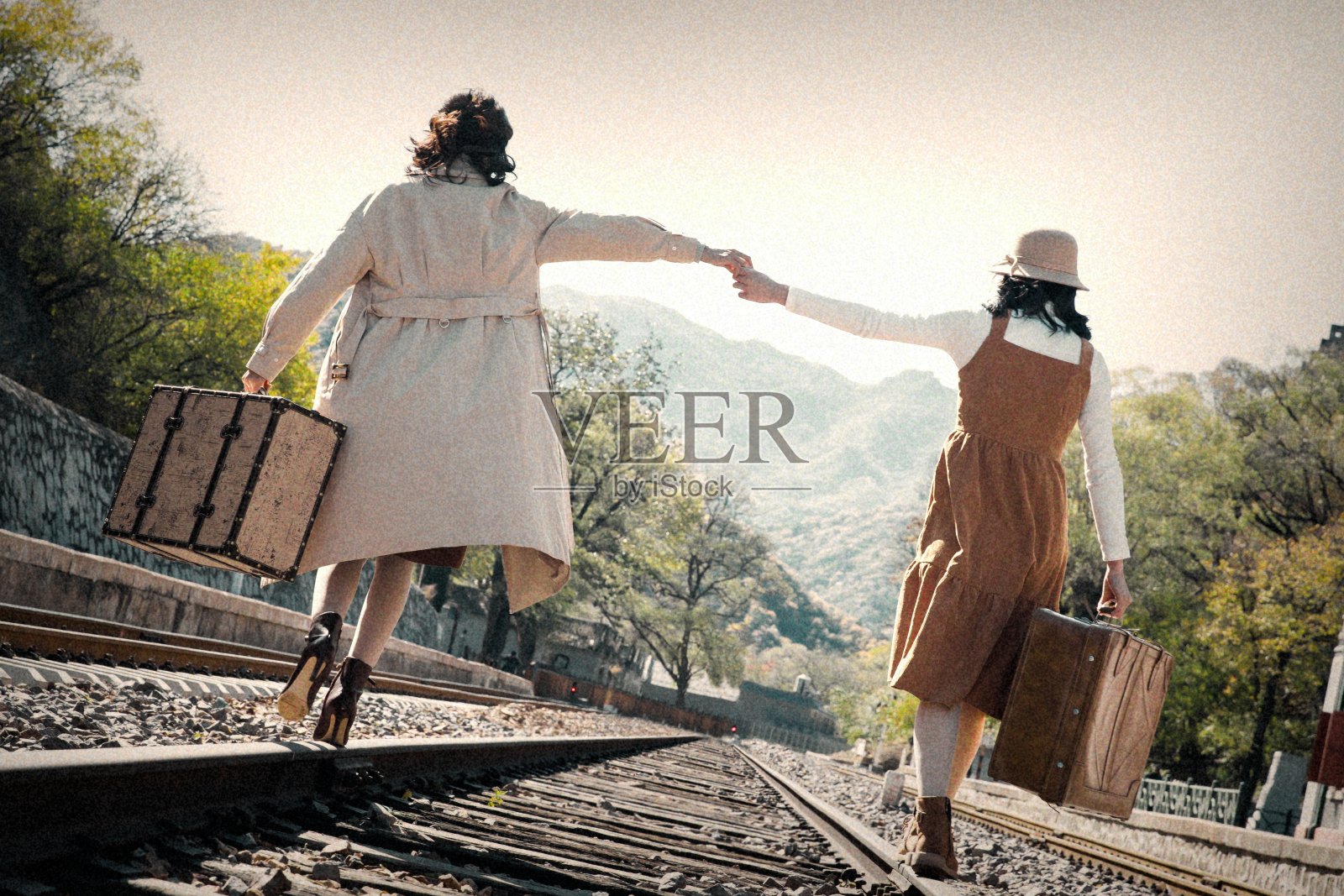 青年闺蜜手牵手走在铁轨上照片摄影图片