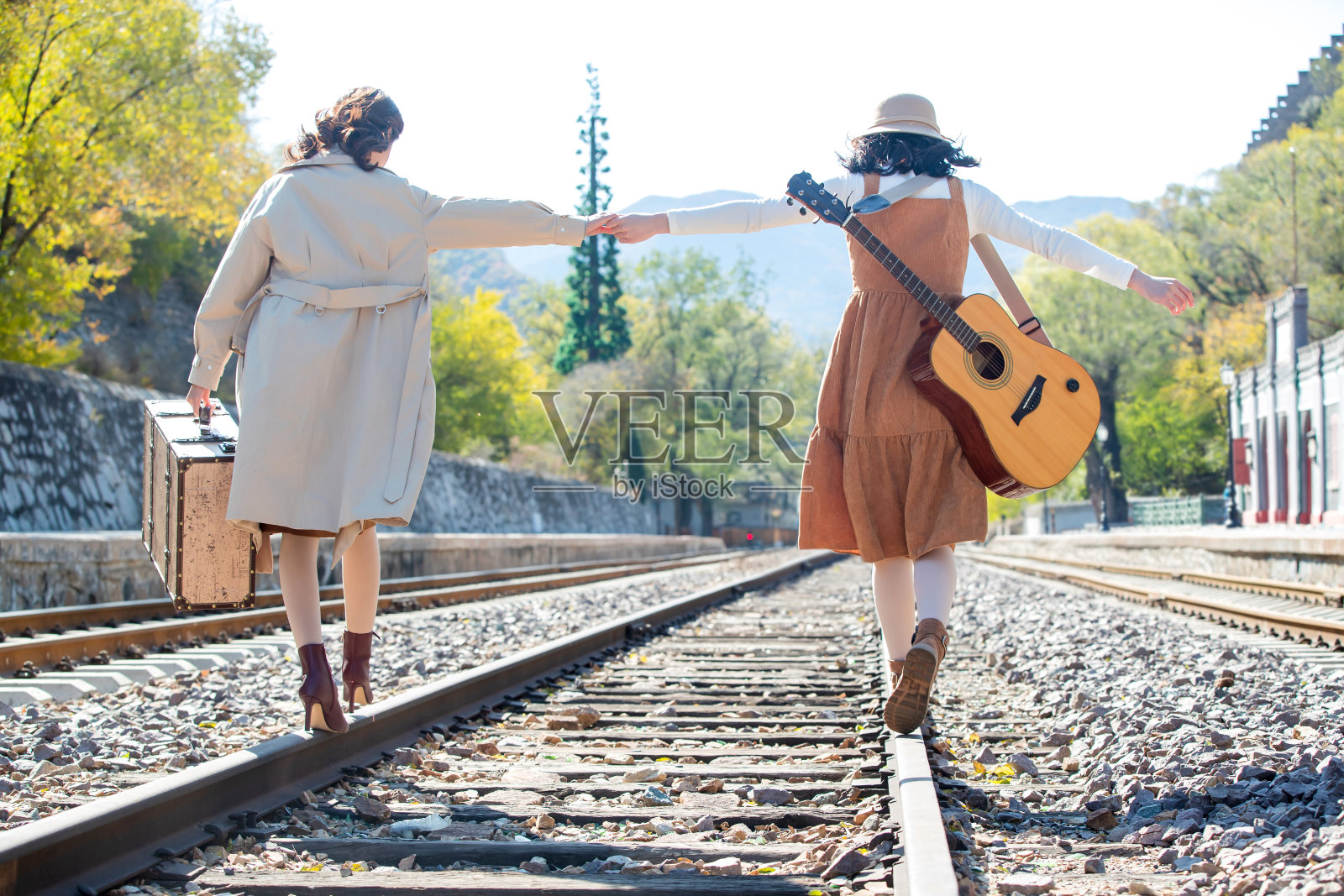 青年闺蜜手牵手走在铁轨上照片摄影图片