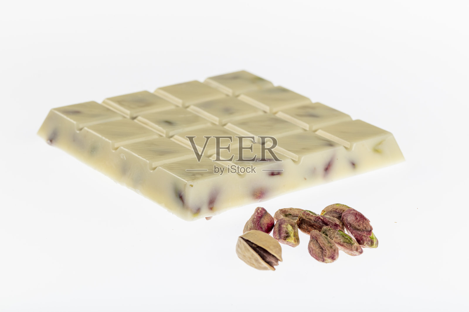 桌上放着白巧克力和巧克力塔。巧克力和开心果。照片摄影图片