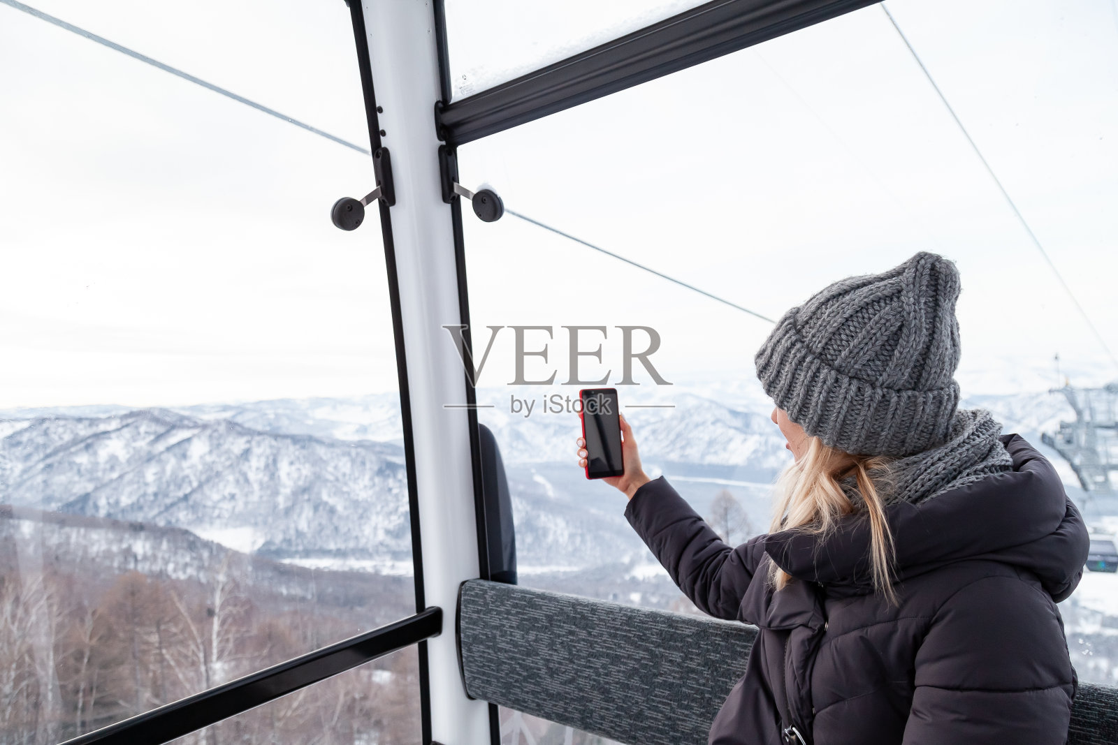 在缆车里拍照的年轻漂亮金发女子照片摄影图片