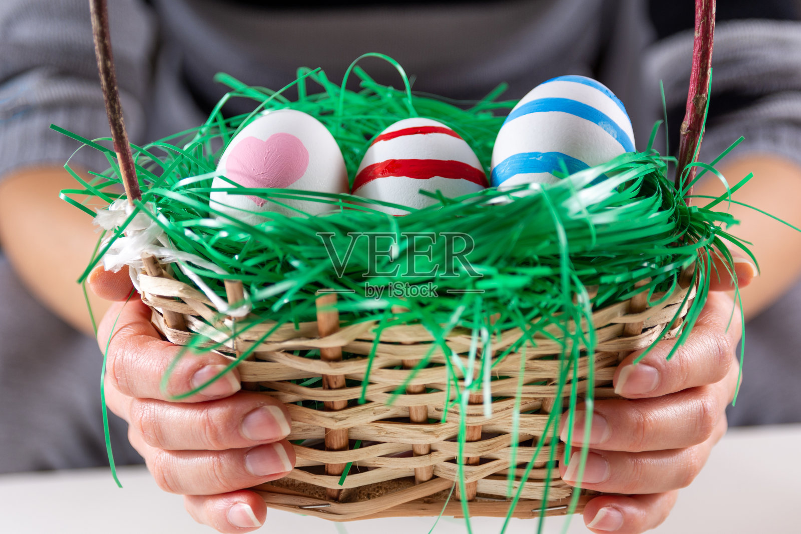 女孩手里拿着复活节彩色的彩蛋，放在一个带绿草的木篮子里照片摄影图片