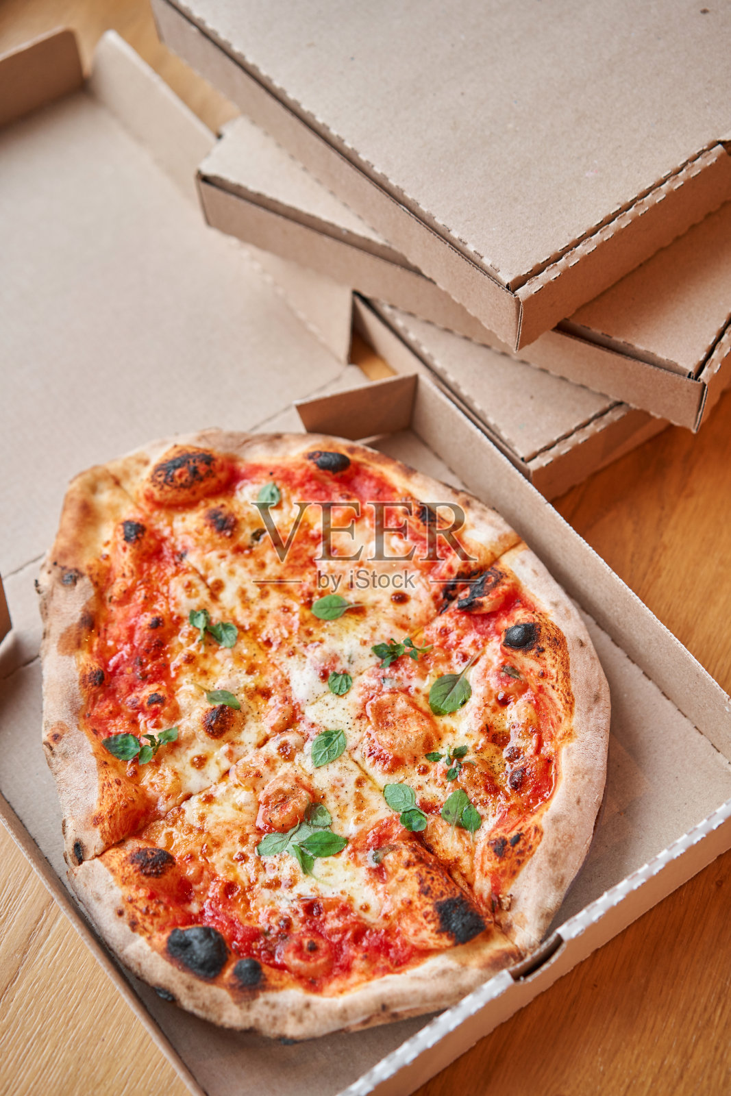 披萨外卖的概念。在木背景下的硬纸盒中烘烤的产品。美味的玛格丽塔披萨在传统的木烤箱，那不勒斯餐厅，意大利。照片摄影图片