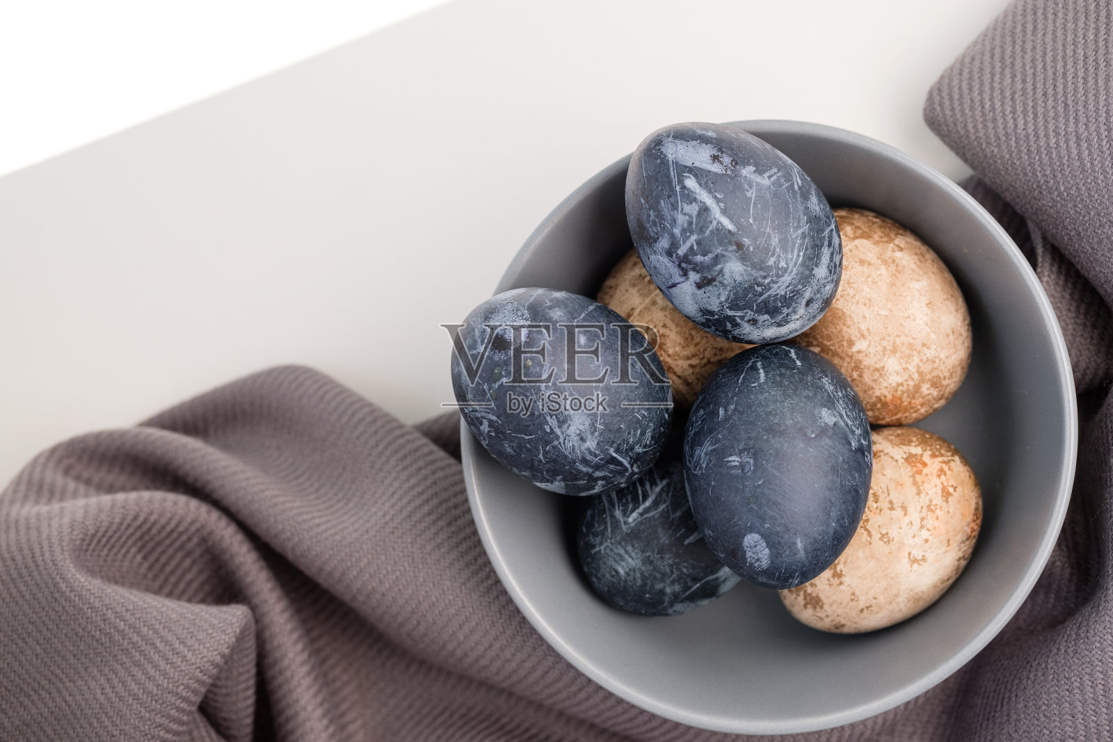 复活节背景与复活节蛋和羽毛在陶瓷灰色碗。复活节彩蛋背景。自然染色的复活节彩蛋在灰色纹理桌布的背景。复活节快乐照片摄影图片