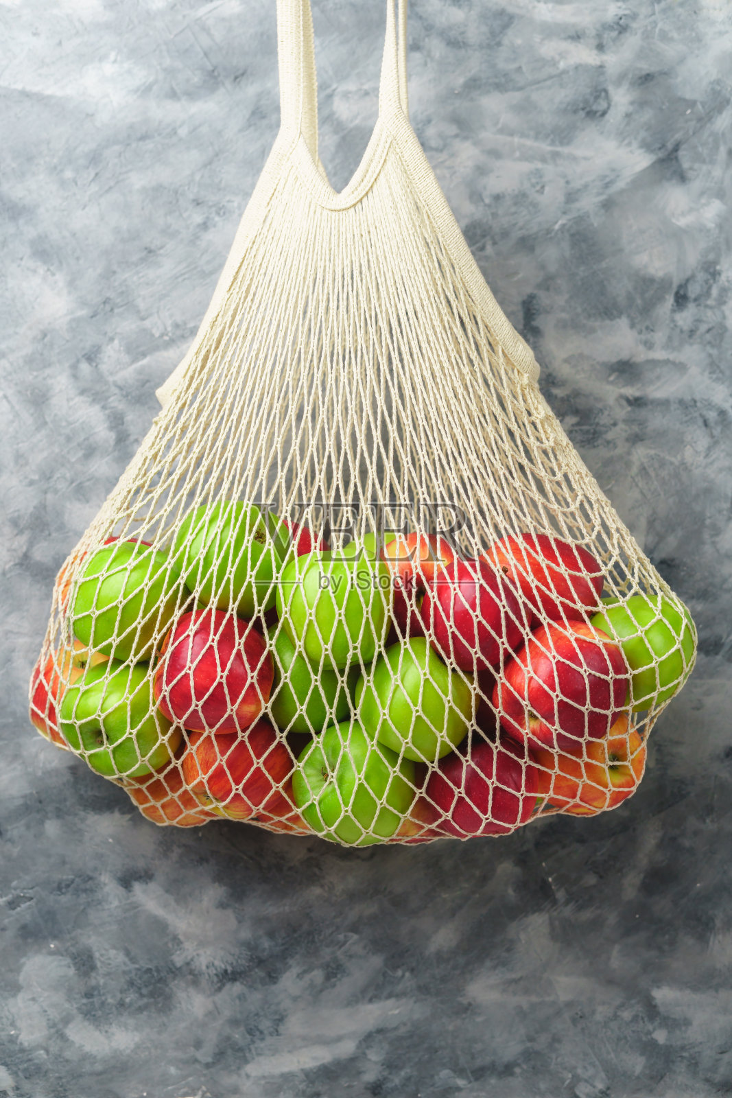 白色的绳袋和红的和绿的苹果。照片摄影图片