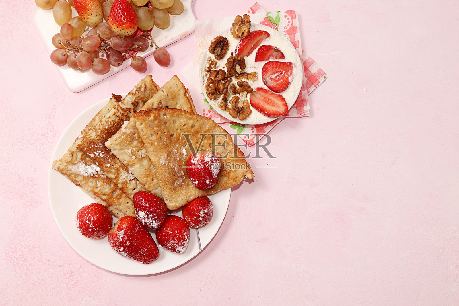 草莓煎饼和格兰诺拉麦片，格兰诺拉麦片在阳光明媚的粉色背景下。健康天然食品的概念。健康的早餐，儿童食物。有选择性的重点。、平面。传统的俄罗斯煎饼和忏悔礼。照片摄影图片