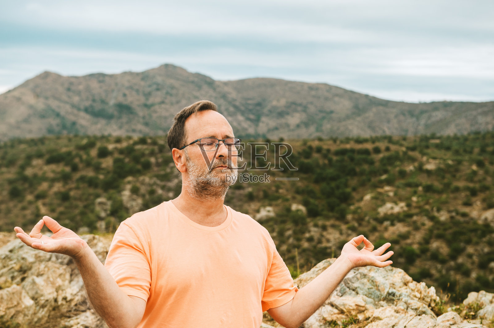 户外人像：英俊的中年男人在山顶冥想放松照片摄影图片