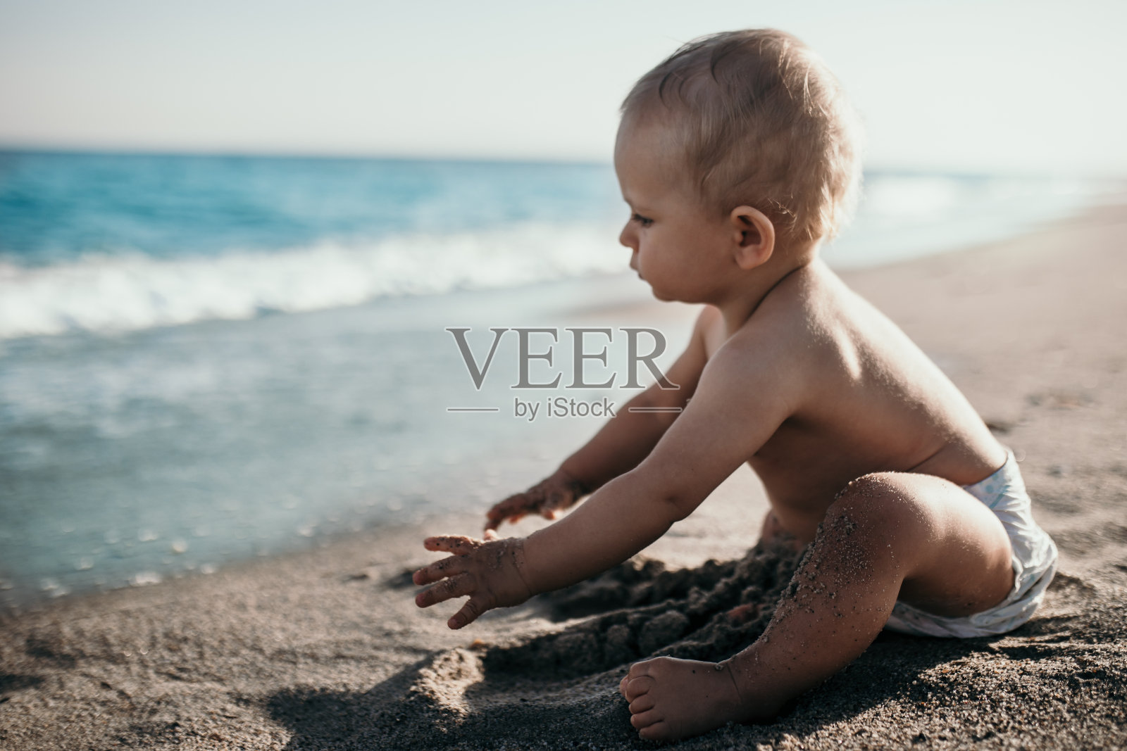 小男孩坐在沙滩上照片摄影图片