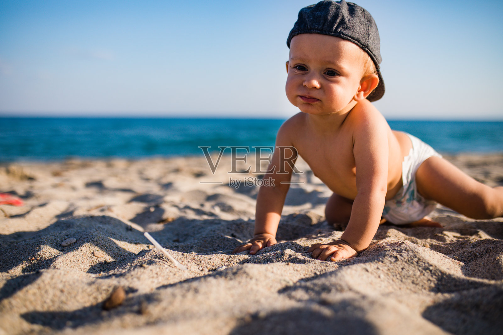 小男孩坐在沙滩上照片摄影图片