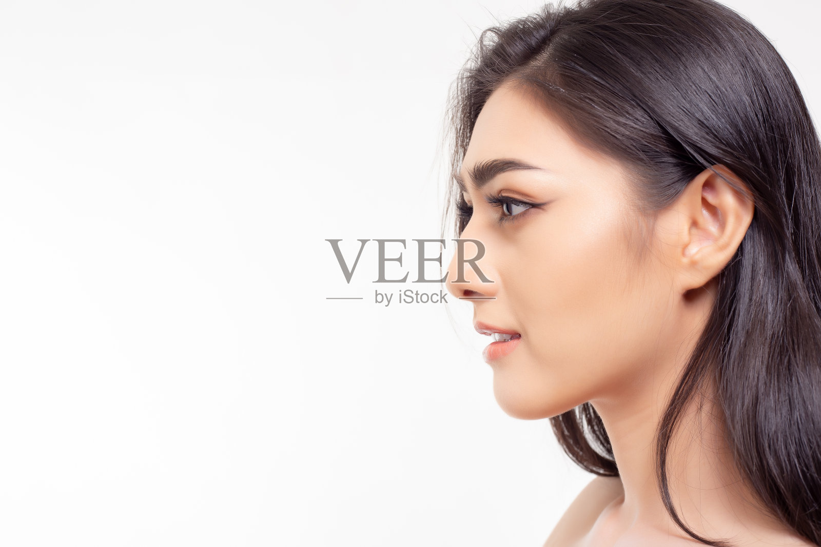 亚洲女人有漂亮的鼻子和漂亮的脸皮肤。漂亮女孩展示左手侧脸。有吸引力的美丽的年轻女子看拷贝空间。她有一头长发。魅力女士化妆自然照片摄影图片