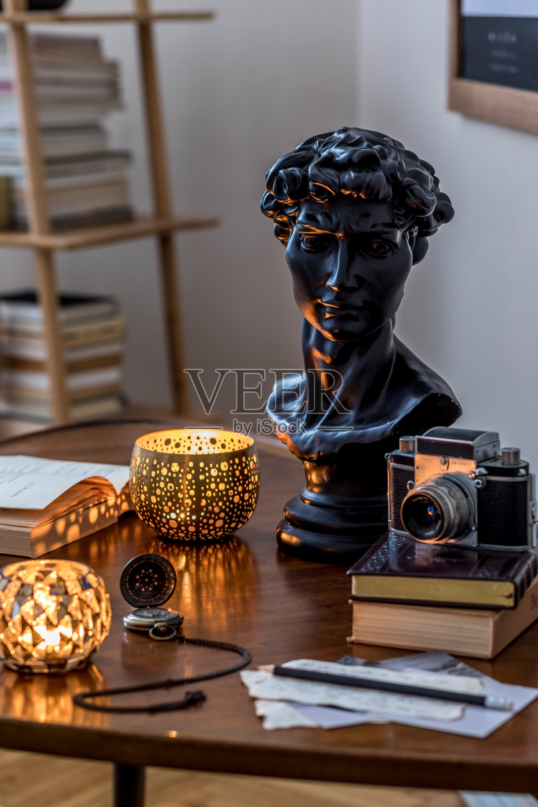 私人图书馆内部的书柜和复古的桌子是优雅的个人配饰的时尚组合。复古的家居装饰。蜡烛，照相机和很多书。模板。关闭了。照片摄影图片