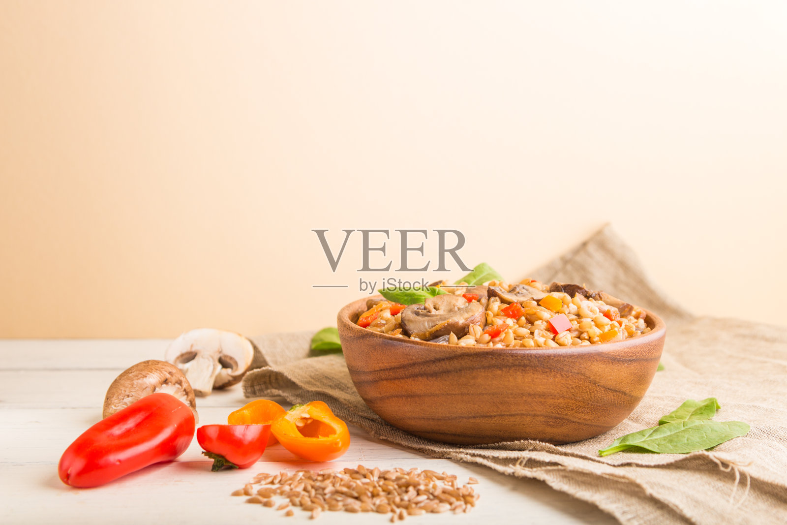 斯匹尔特小麦粥与蔬菜和蘑菇木碗在白色和橙色的背景和亚麻纺织品。侧视图，选择性聚焦，复制空间。照片摄影图片