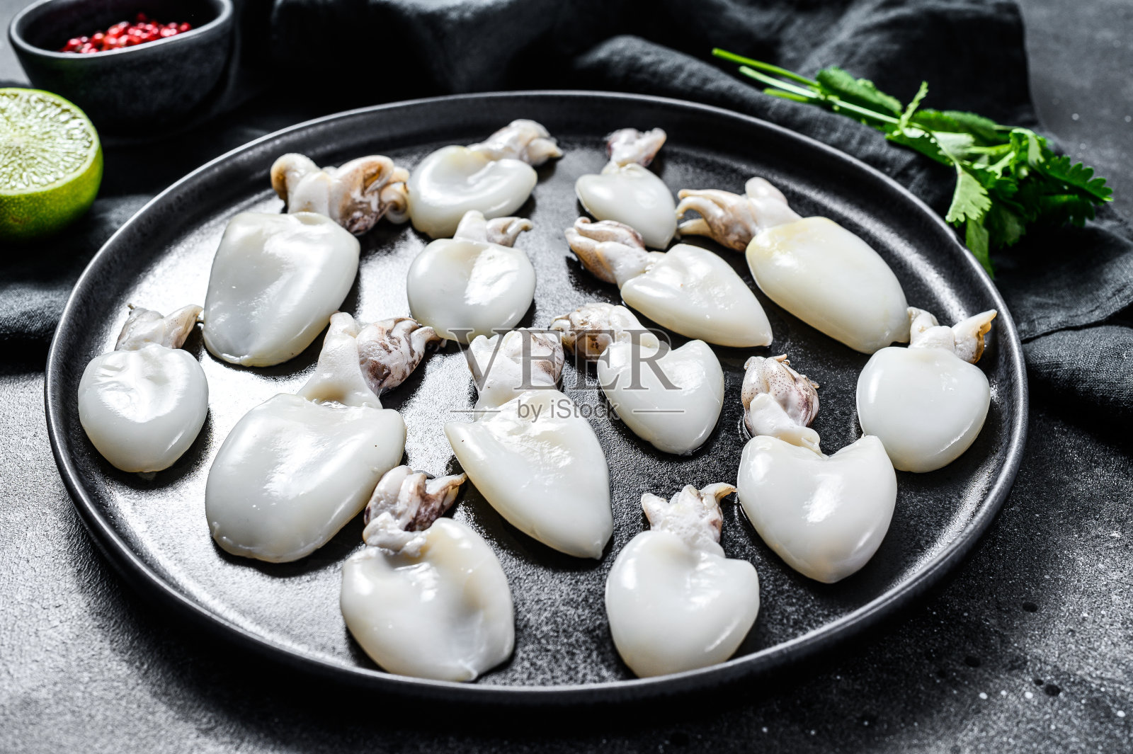 生墨鱼配迷迭香和欧芹碟。黑色背景。俯视图照片摄影图片