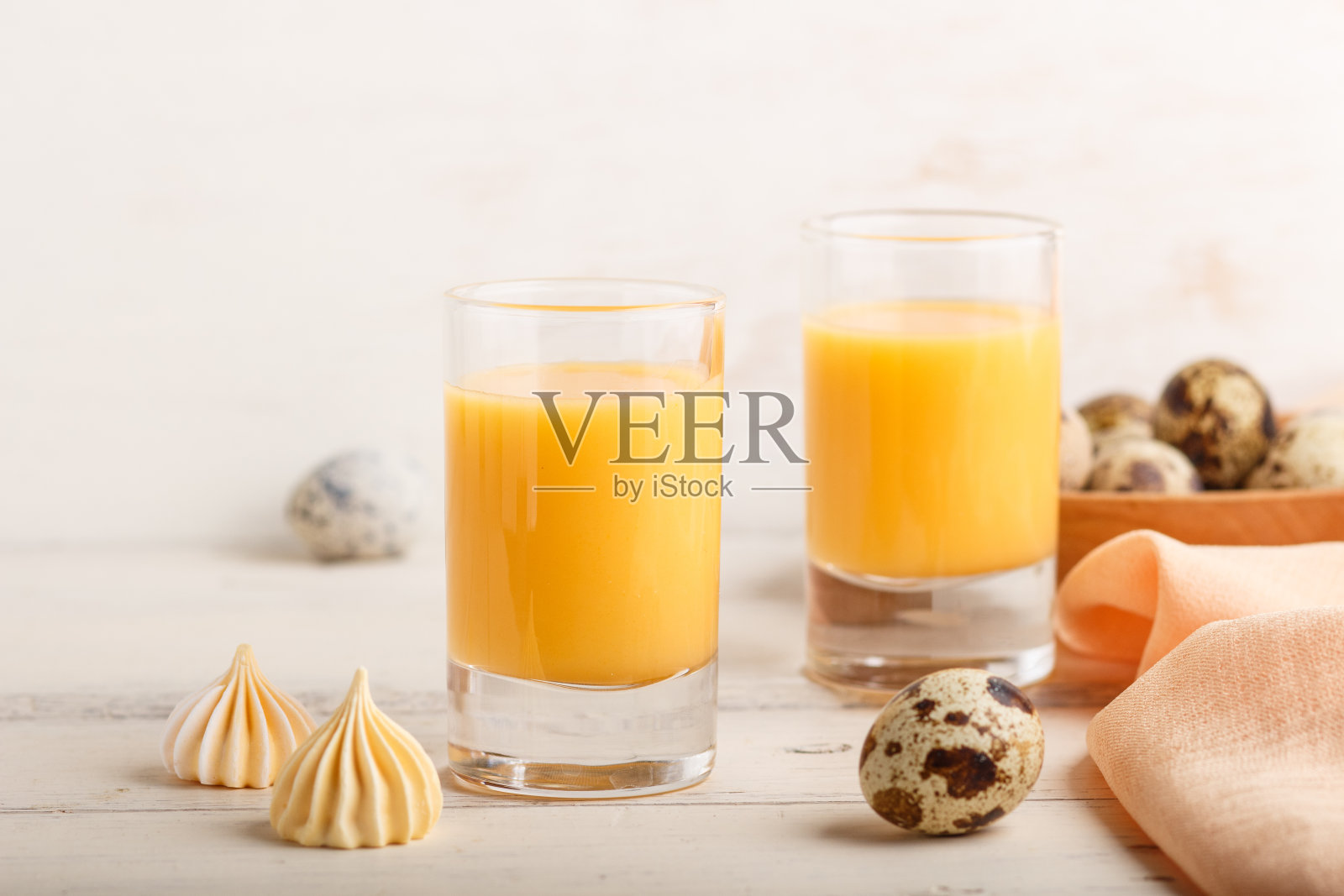 甜蛋利口酒，以鹌鹑蛋和蛋白糖霜为背景，白色木质。侧视图，闭合，高键。照片摄影图片