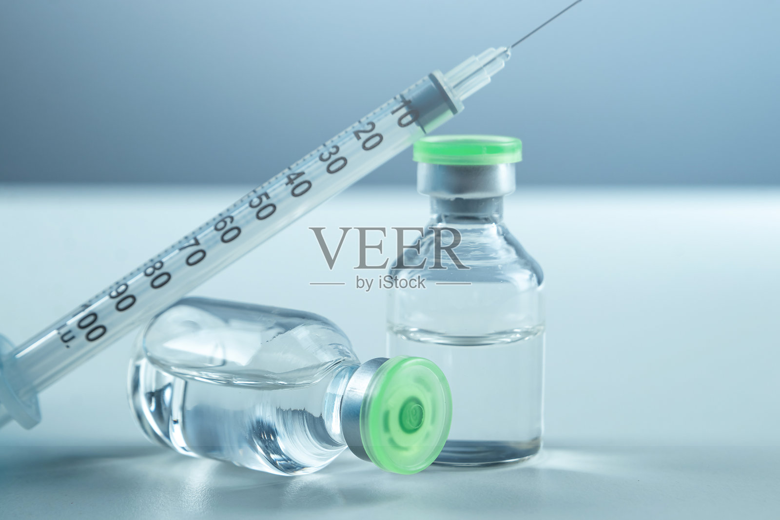 白色桌面上的疫苗瓶和注射器特写，灰色背景，医学概念，实验室，皮下注射疫苗，剂量。疾病治疗免疫。照片摄影图片